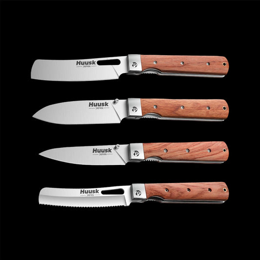 Four Huusk folding kitchen knives with natural wood handles arranged on black.