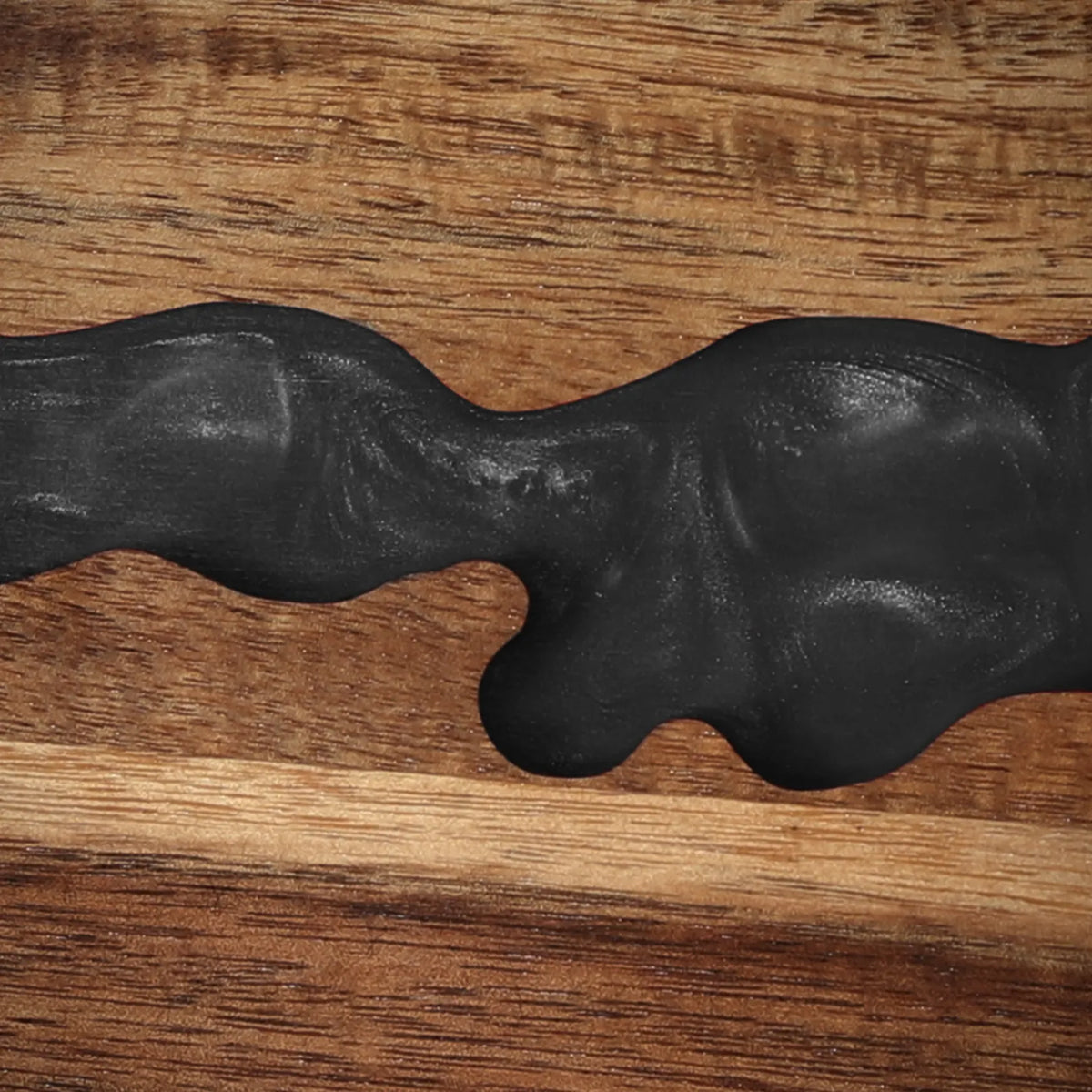 Close-up of the obsidian-black resin river detail in the acacia magnetic knife block
