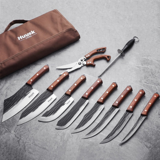 Ten-piece Huusk kitchen knife set arranged beside its brown roll case on a gray surface.
