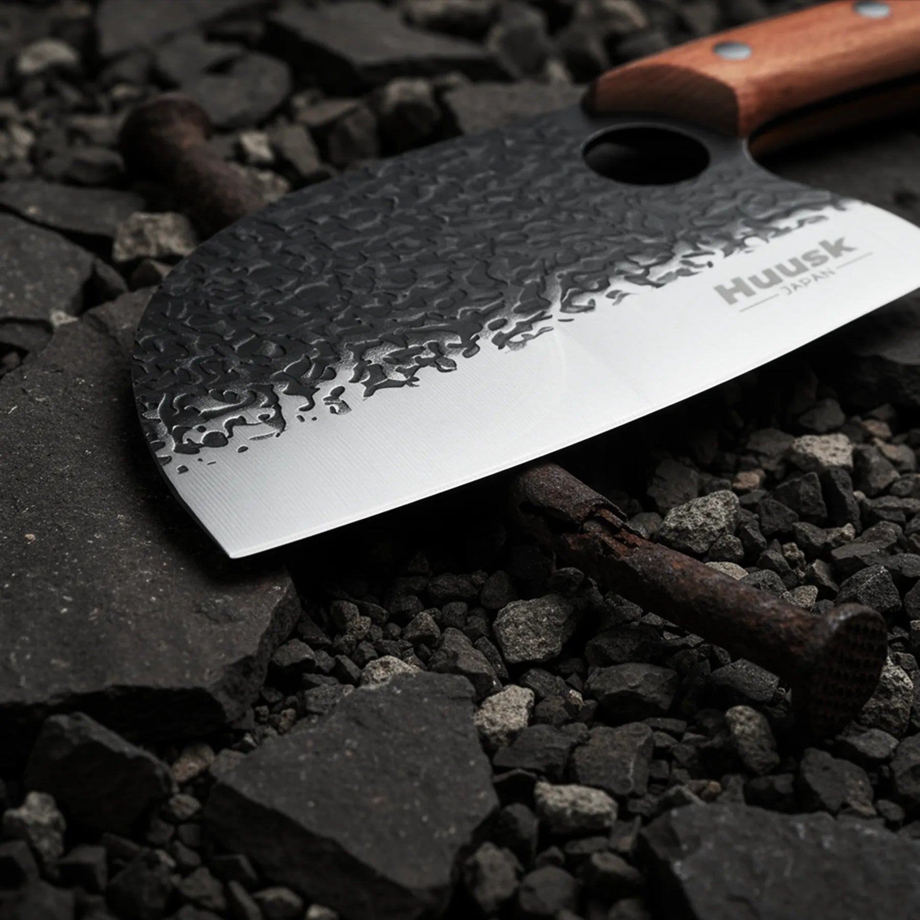 Close-up of a Huusk cleaver's hammered blade, polished cutting edge, and finger hole.