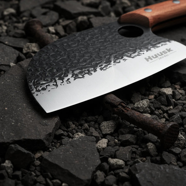 Close-up of a Huusk cleaver's hammered blade, polished cutting edge, and finger hole.