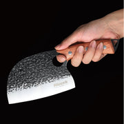 Hand holding a Huusk forged cleaver against a black background to show grip and scale.