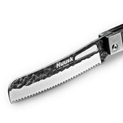 Close-up of the Huusk camo folding bread knife's hammered serrated blade.