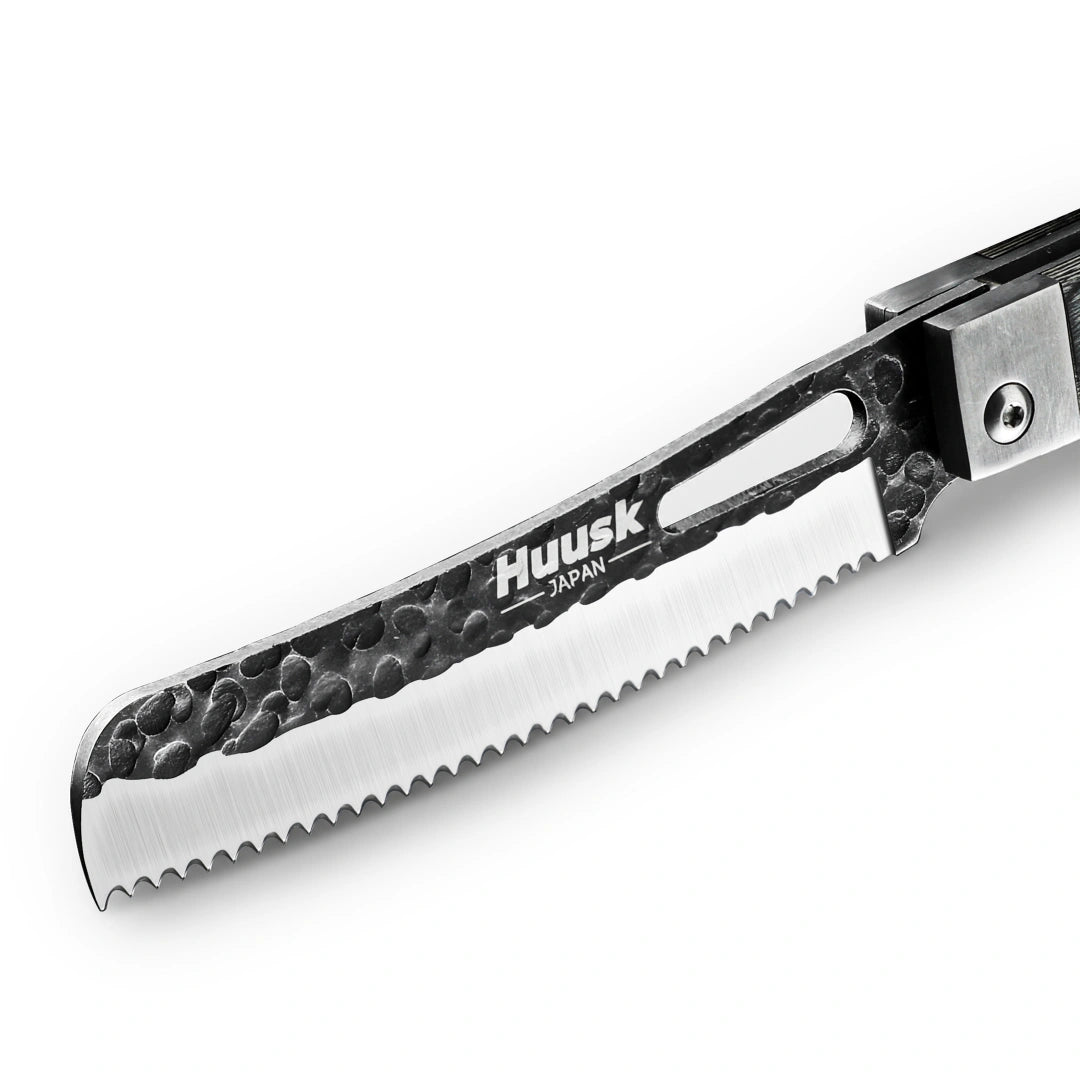 Close-up of the Huusk camo folding bread knife's hammered serrated blade.
