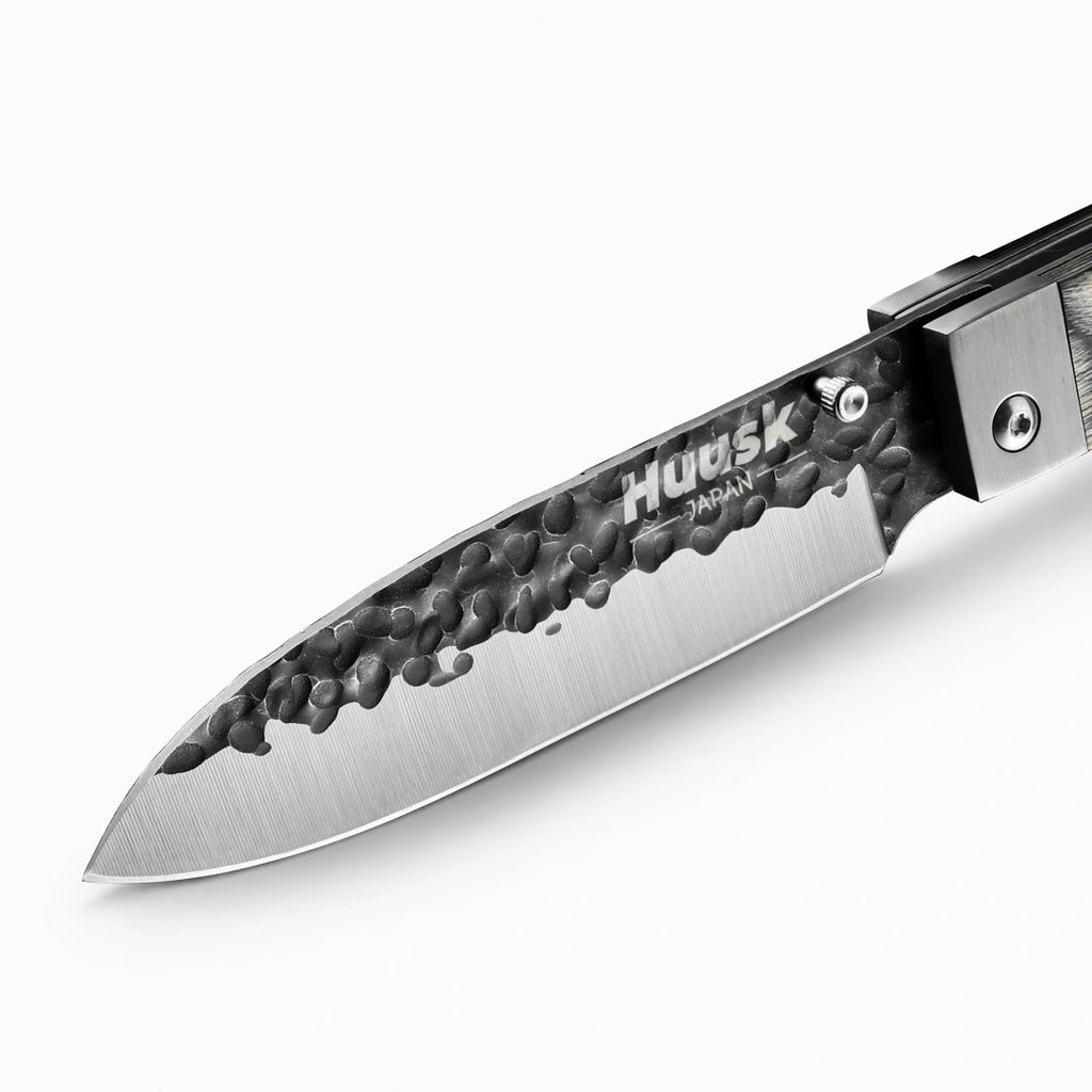 Close-up of the Huusk camo folding chef knife's hammered blade and polished edge.