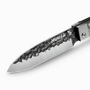 Close-up of the Huusk camo folding chef knife's hammered blade and polished edge.
