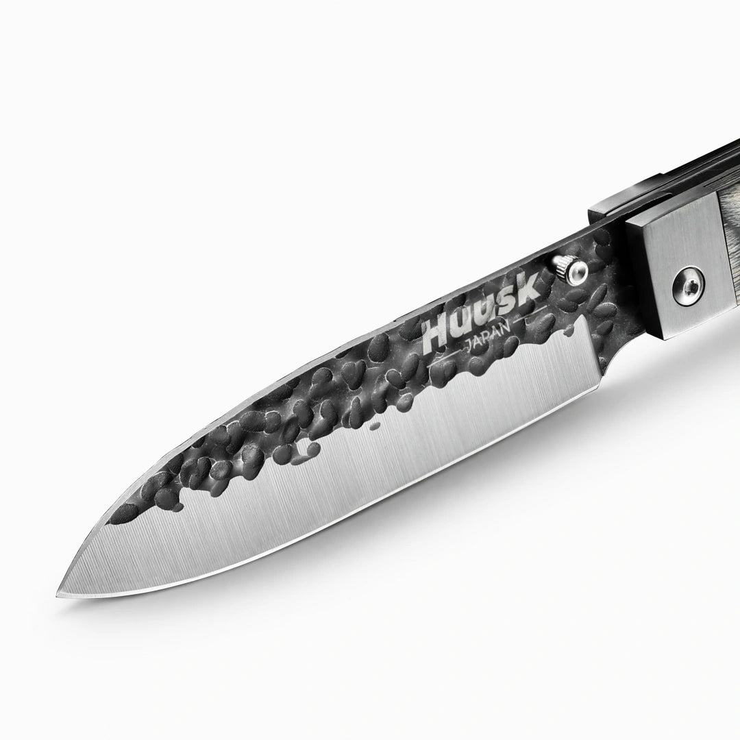 Close-up of the Huusk camo folding chef knife's hammered blade and polished edge.