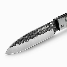 Close-up of the Huusk camo folding chef knife's hammered blade and polished edge.