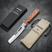 Huusk natural wood folding bread knife displayed open with its box and storage pouch.